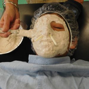 Teaching artist Kit Sailer applies a cast to a student's face at Sussex Avenue School, Newark.